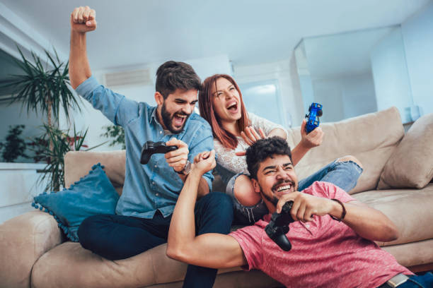 Group of young friends play video games together at home. stock photo