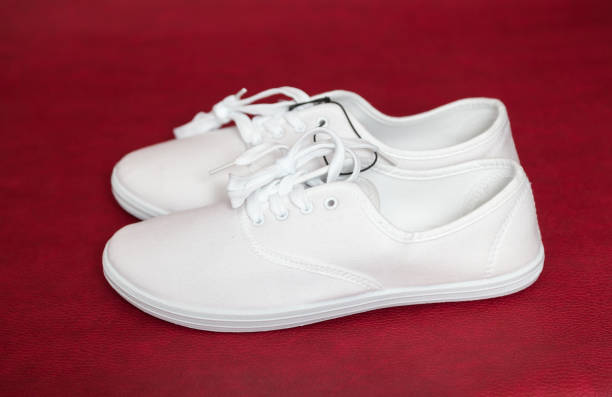 istock Pair of white sneakers standing on red background. 1072095682