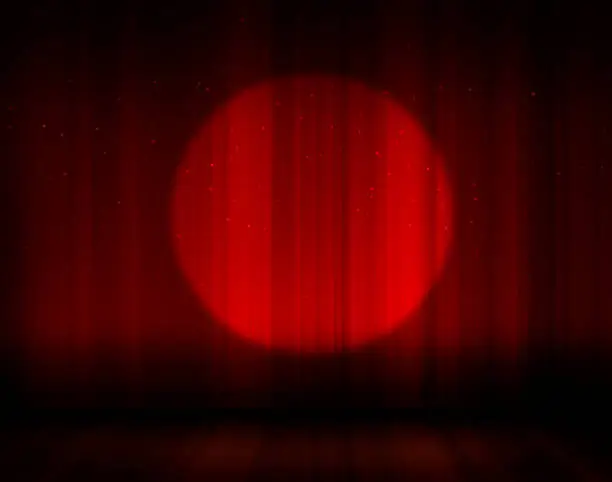 Stage with red curtains and one light beam on it