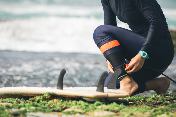 istock woman surfer tying leg leash with surfboard on seaside reef 1072111140
