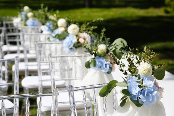 Ice cubes with blue flowers inside stand before transparent plastic chairs