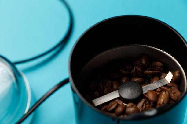 istock Electric coffee grinder with roasted coffee beans on the kitchen table with blue tabletop. Close-up 1072134802