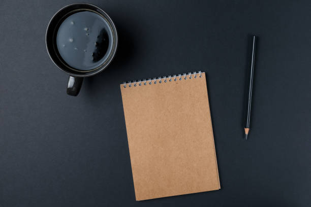 istock Blank notebook with pencil and Cup of coffee on black background. Workplace. Copy space. Minimal concept. Top view. Flat lay 1072135054
