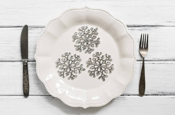 istock Christmas table setting ,silver snowflakes on a white plate, vintage cutlery, fork and knife. White wooden wooden table. Top view, flat lay. 1072138812