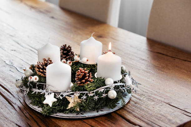 зажигание первой свечи на адвент венок в первое воскресенье декабря, чтобы отпраздновать начало рождественских праздников в швейцарии - advent wreath candle christmas стоковые фото и изображения