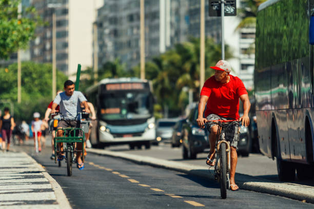 anciano brasileño paseos en bicicleta a lo largo de un carril bici junto a la playa de copacabana - brazil bicycle rio de janeiro outdoors fotografías e imágenes de stock
