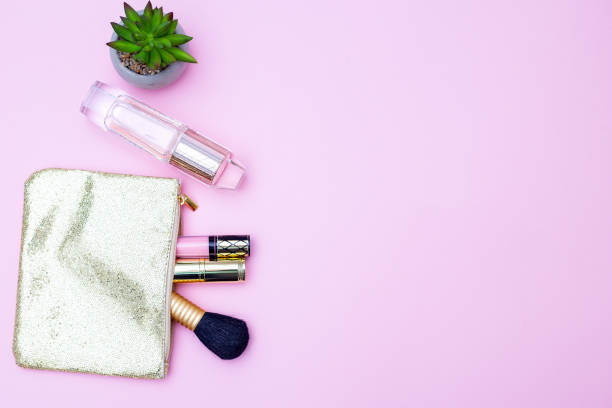 istock Shiny golden cosmetic bag and perfume on a pink background. Copy space 1072152952