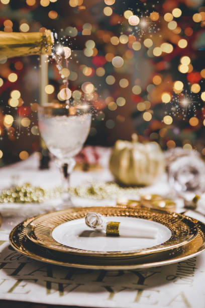 New year table setting Pouring champagne on a luxury golden glass, New year and christmas table setting with exclusive and luxury golden cutlery, over a tabletop with celebrations world " new year" place setting table plate dining table stock pictures, royalty-free photos & images