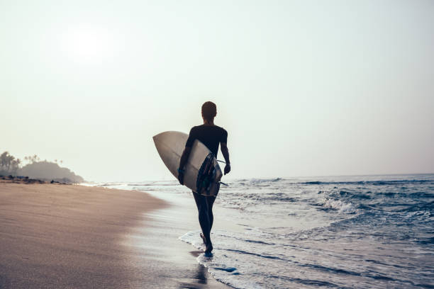 istock Surfer woman with surfboard walking on tropical beach 1072167202