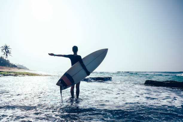 istock Happy woman surfer with surfboard on mossy seashore 1072171536