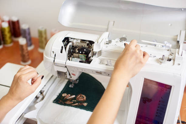 istock Close-up of woman operator hands filling thread in modern white sewing machine. 1072183310