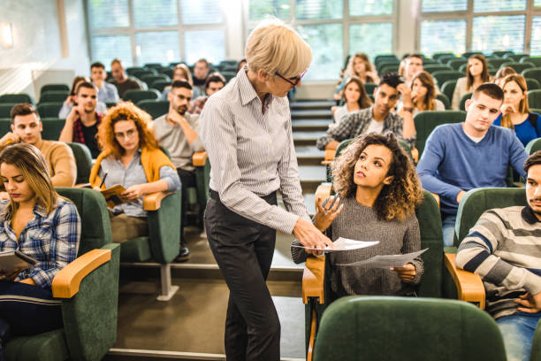 istock Female college student talking to senior professor on a class at lecture hall. 1072191510
