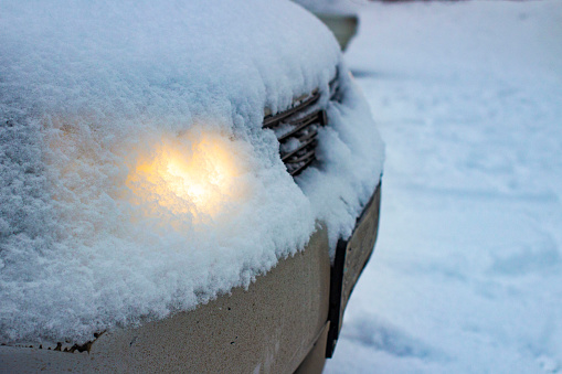 glowing head light car headlights through a layer of snow fell from the sky