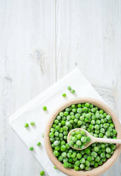 istock frozen peas on wooden surface 1072198102
