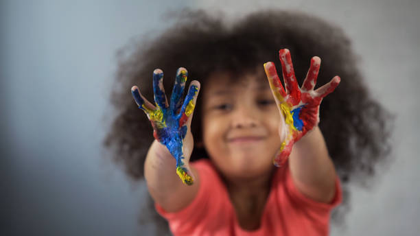 criança do sexo feminino africana alegre se divertindo e mostrando palmeiras pintadas para câmera - child art paint humor - fotografias e filmes do acervo