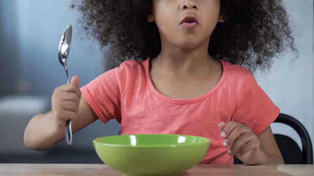istock Playful preschool girl asking for dinner, sitting at table with spoon, nutrition 1072201730