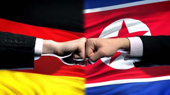 Germany vs North Korea conflict, fists on flag background, diplomatic crisis