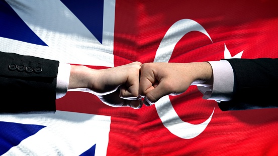 Great Britain vs Turkey conflict, fists on flag background, diplomatic crisis
