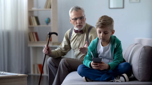 istock Upset grandfather scolding grandson for using cell phone, internet addiction 1072204226