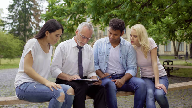 istock Students and teacher sitting in park near college, discussing science project 1072205202