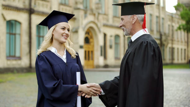 istock University chancellor giving diploma to student, congratulating and shaking hand 1072208038