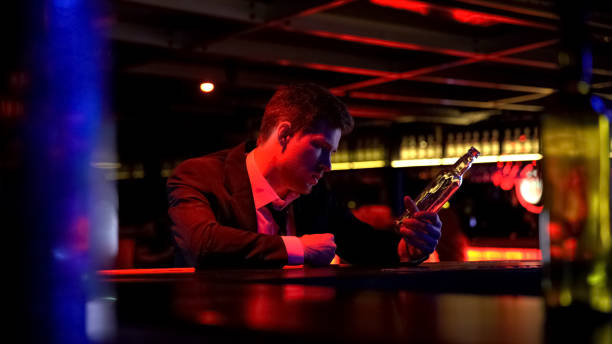 istock Drunk man alone stays late in bar, finishes whiskey bottle, suffering depression 1072208086