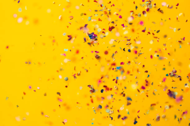Confetti rain on yellow background. Directly above shot.