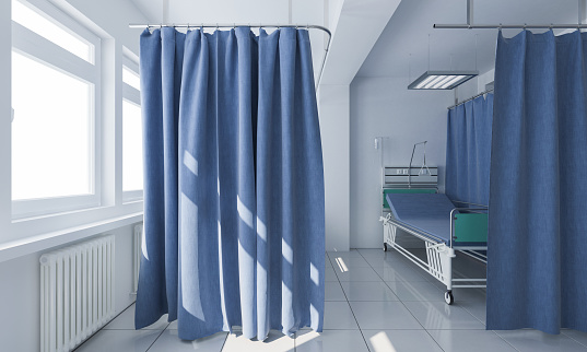Cama con ruedas detrás de cortinas de privacidad en una clínica médica photo