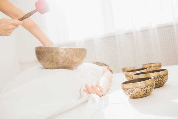 Young beautiful girl doing massage therapy singing bowls in the Spa. The concept of relaxation and alternative medicine. Toning.