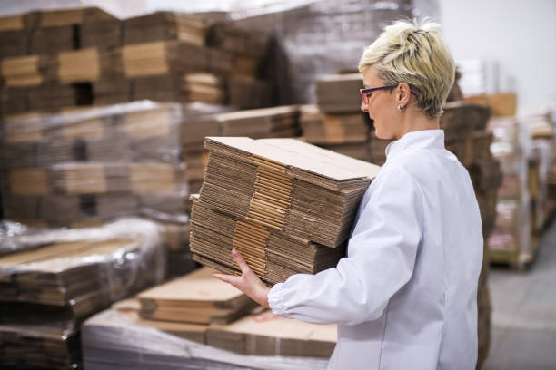 istock Woman carrying unmade cardboard boxes. Side view, warehouse interior. 1072244978