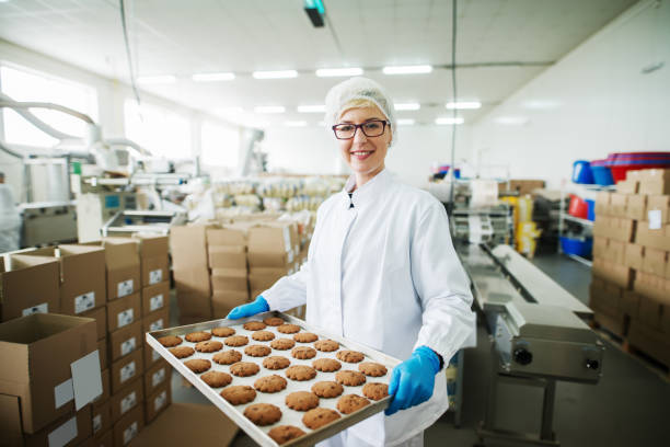 istock Female worker standing and holding plate with cookies. 1072247016
