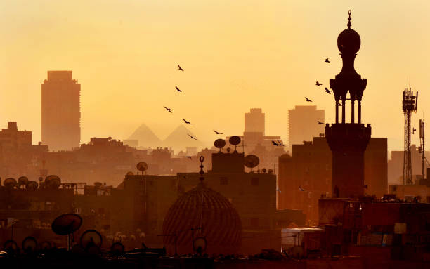 Cairo skyline and pyramids The skyline of Cairo at sunset with birds over domes and satellite dishes with distant pyramids at Giza cairo stock pictures, royalty-free photos & images