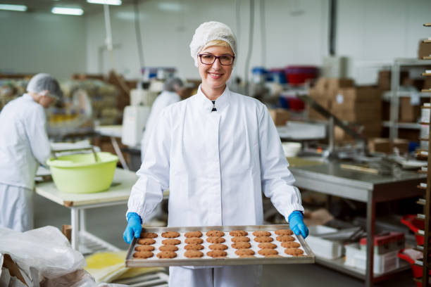 istock Female worker standing and holding plate with cookies. 1072247428