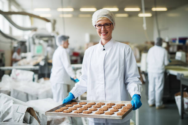 istock Female worker standing and holding plate with cookies. 1072247682