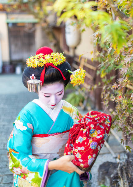 istock Maiko Apprentice Geisha walking under maple leaves 1072249370