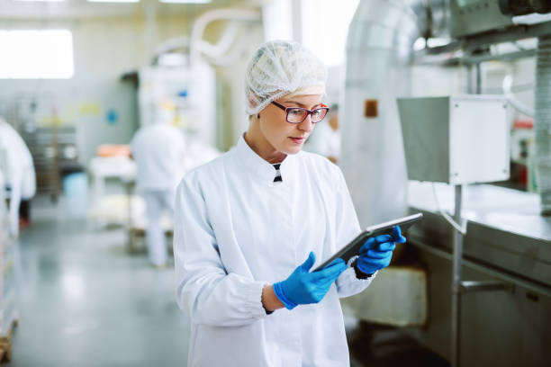 istock Female worker using tablet for controling products while standing in food factory. 1072249434