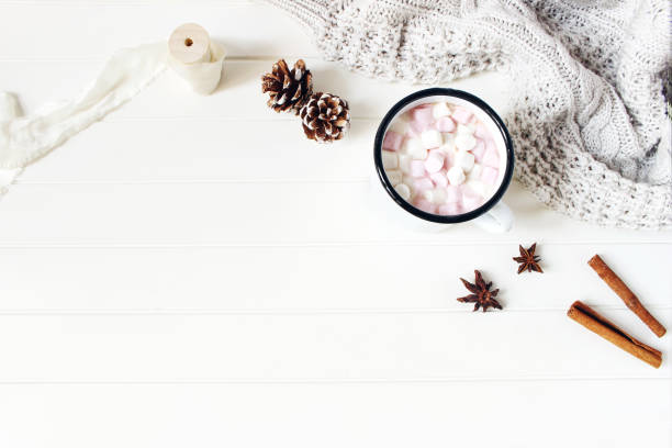 istock Christmas styled composition. Hot chocolate, marshmallow,cinnamon sticks, anise stars, pine cones and knitted blanket on white wooden table background. Winter breakfast concept. Flat lay, top view. 1072249934