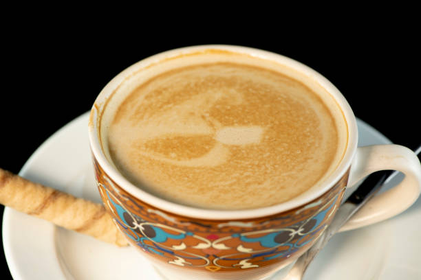 Stock photo showing close-up view of a freshly made hot cup of Americano coffee (espresso and water) in a white, china cup and saucer, isolated on a black background.