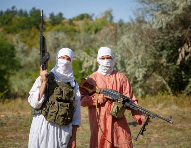 Veiled soldiers in traditional muslim clothes with guns in their hands stock photo