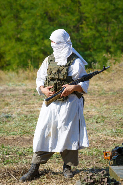 veiled soldier in traditional islamic white clothes with the kalashnikov gun - jihad imagens e fotografias de stock