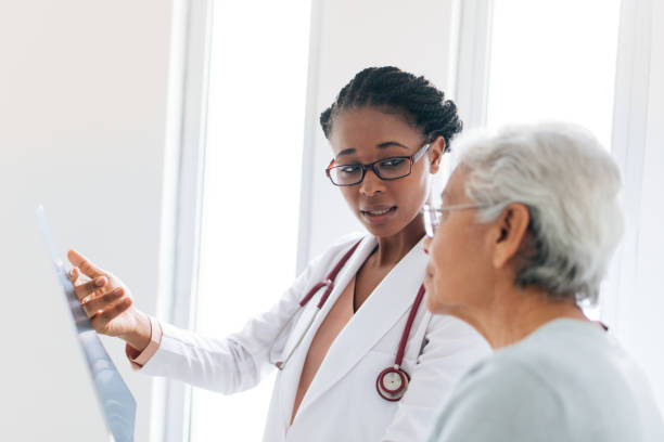 medico donna che mostra raggi x a paziente anziano - physicians assistant foto e immagini stock