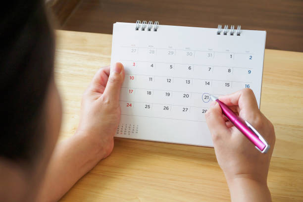 istock calendar page with female hand holding pen on desk table 1072287046