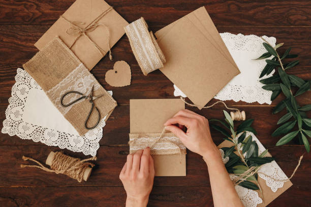 istock Flat lay Tools DIY on a wooden table: paper, scissors, thread, olive branch. Self-made envelope for letters. Top view. 1072287778