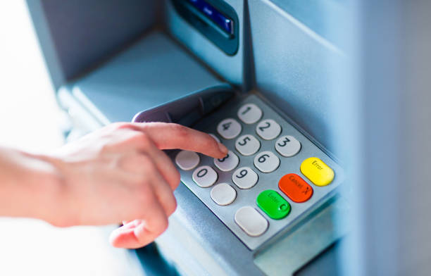 A person withdrawing money from a atm machine Close-up of hand entering PIN/pass code for a money transfer, on a ATM/bank machine keypad outside atm photos stock pictures, royalty-free photos & images