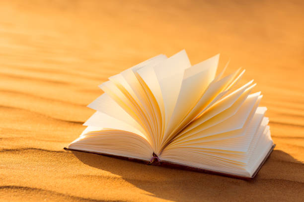 istock A open book with pages turning on the desert sand. 1072288278