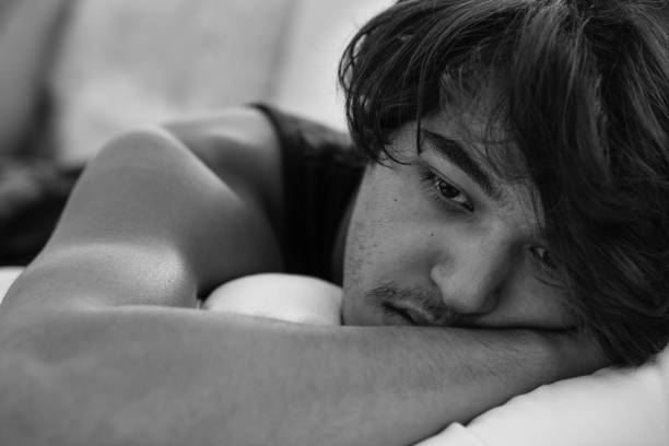 istock Depressed sad young man lying in bed. Black and white. 1072288280