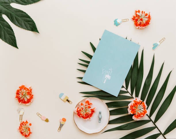 Flat lay creative background with empty blue card, flowers and tropical leaves