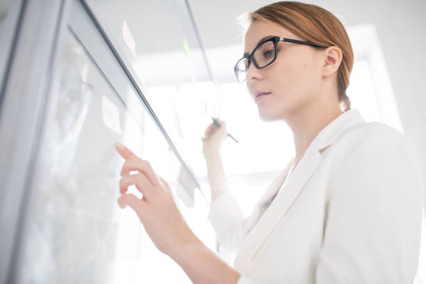 istock Serious businesswoman drawing on whiteboard 1072306790