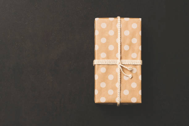 Gift wrapped with spotty paper on black textured background. Directly above table top shot