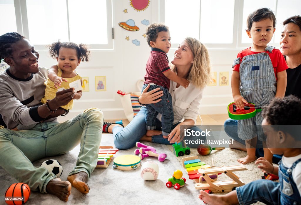 Bambini diversi che si divertono a giocare con i giocattoli - Foto stock royalty-free di Genitori